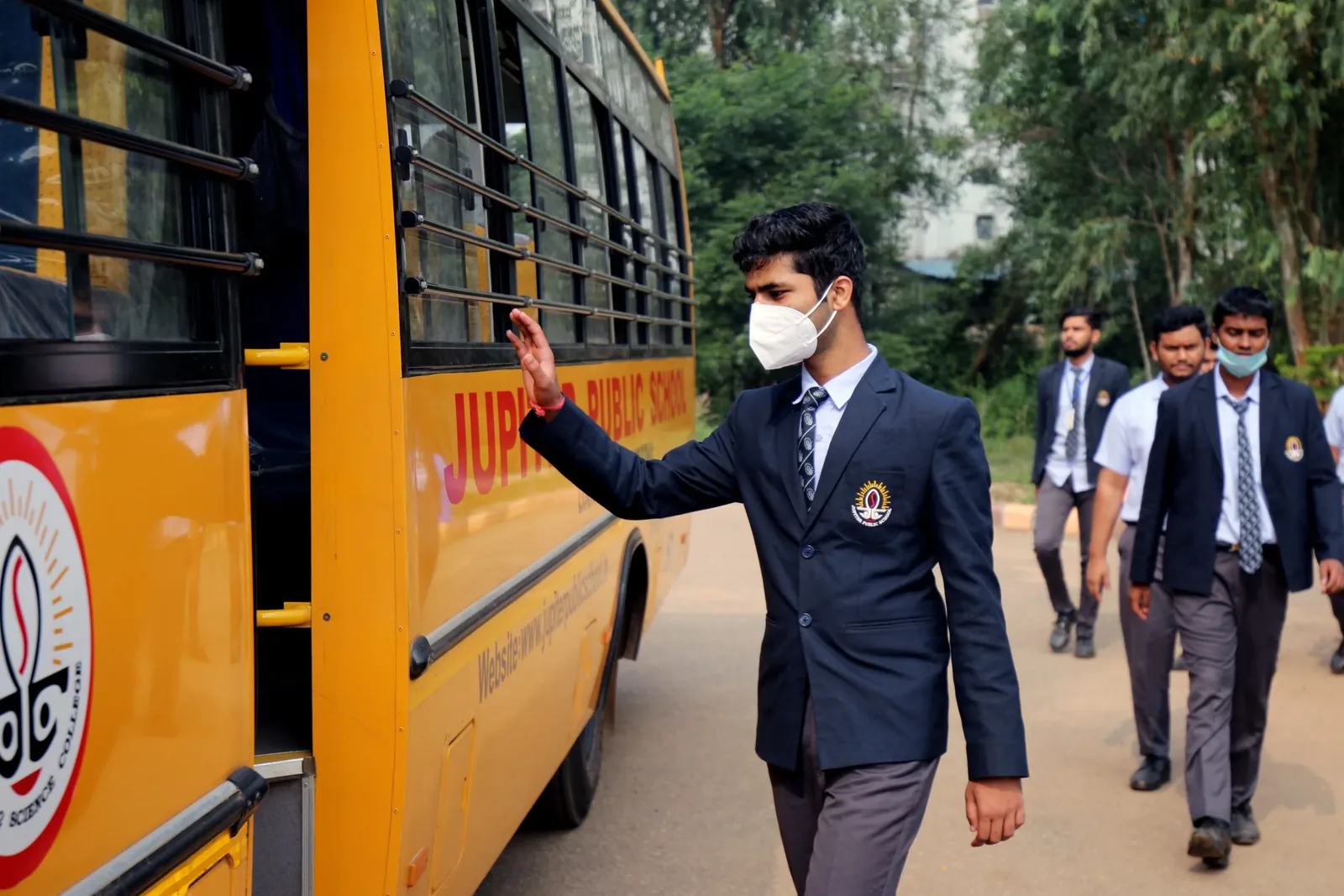 Students in school blazers boarding a yellow Jupiter school bus