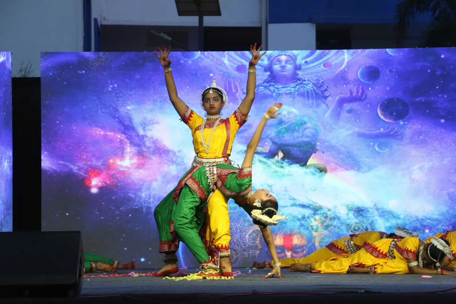 Solo classical Odissi dancer performing on the school stage.