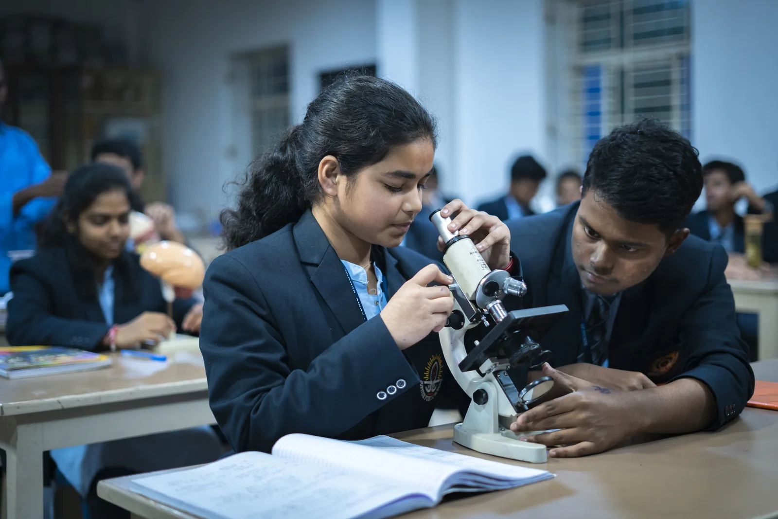 Senior students in uniform operating laboratory compound microscopes.