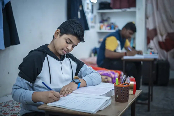 A boarder writing notes during supervised evening prep.