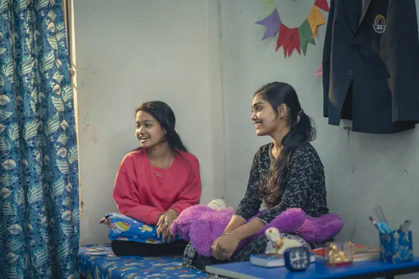 Two girl boarders relaxing in their brightly lit hostel room.