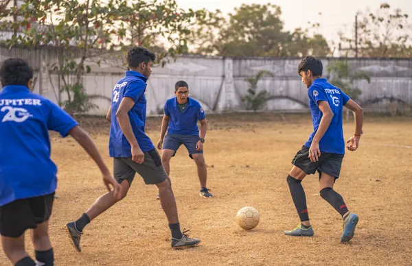 Student striking a football on the campus ground.