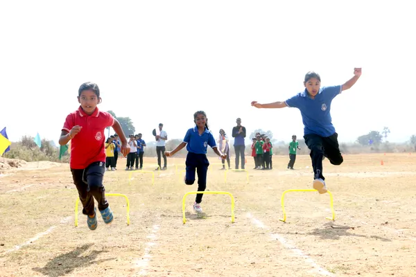 Junior students sprinting over hurdles at the annual sports meet.