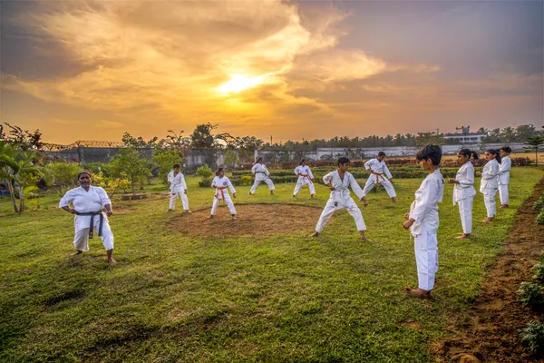 Students in white karate uniforms training on the campus lawn.