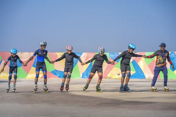 Inline skaters in helmets and knee guards lined up on the school rink.